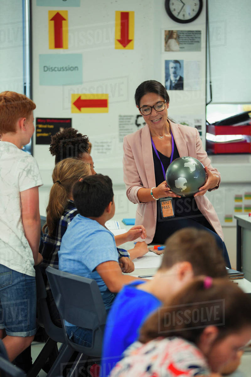 Female geography teacher with globe teaching lesson in classroom