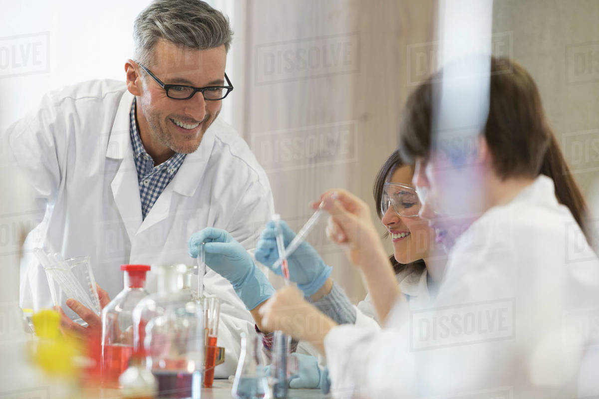 Male science teacher and students conducting scientific experiment