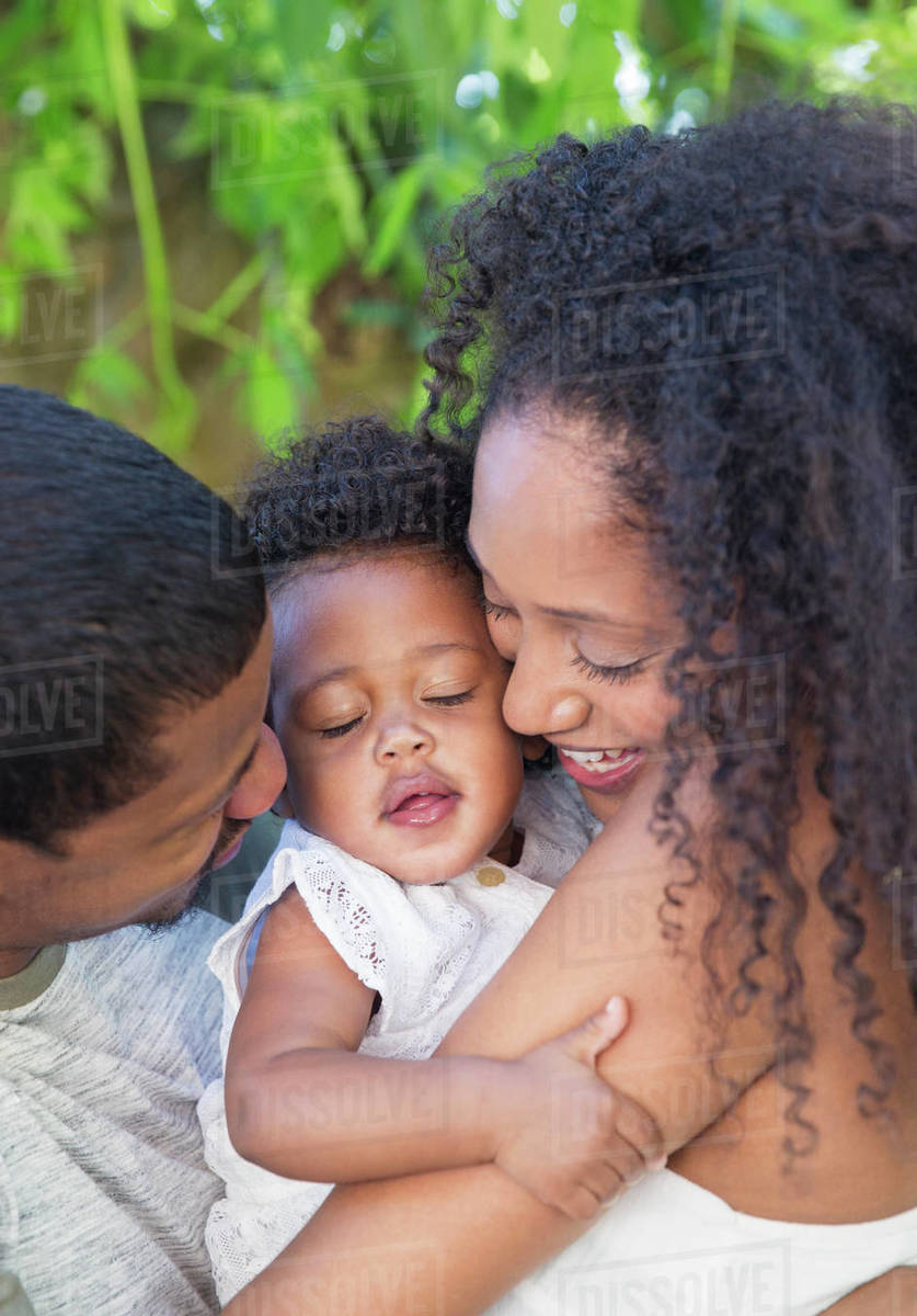 Affectionate couple hugging toddler daughter Stock Photo Dissolve