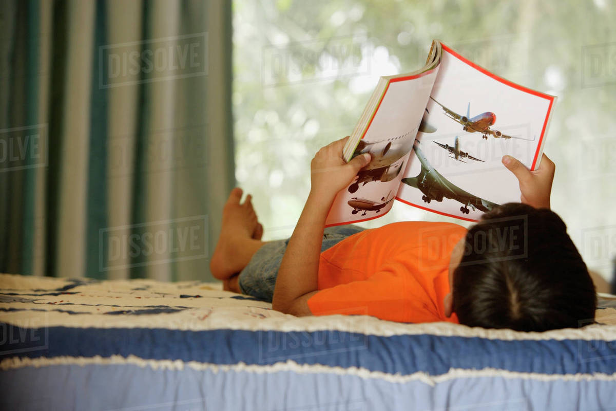 Boy reading on bed Stock Photo Dissolve