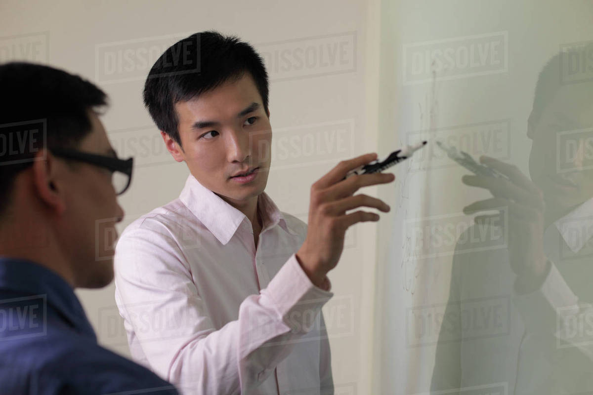 Man explaining something on white board. Stock Photo Dissolve