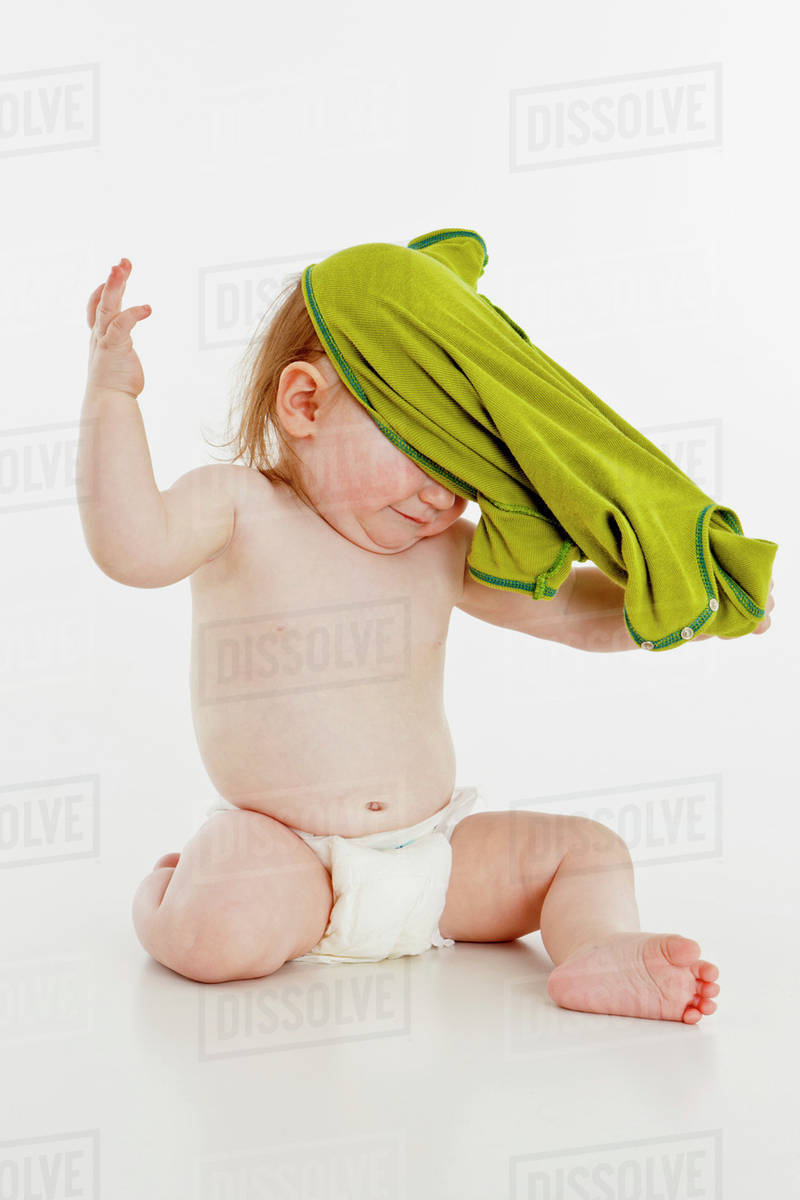 A baby girl pulling her shirt off Stock Photo Dissolve