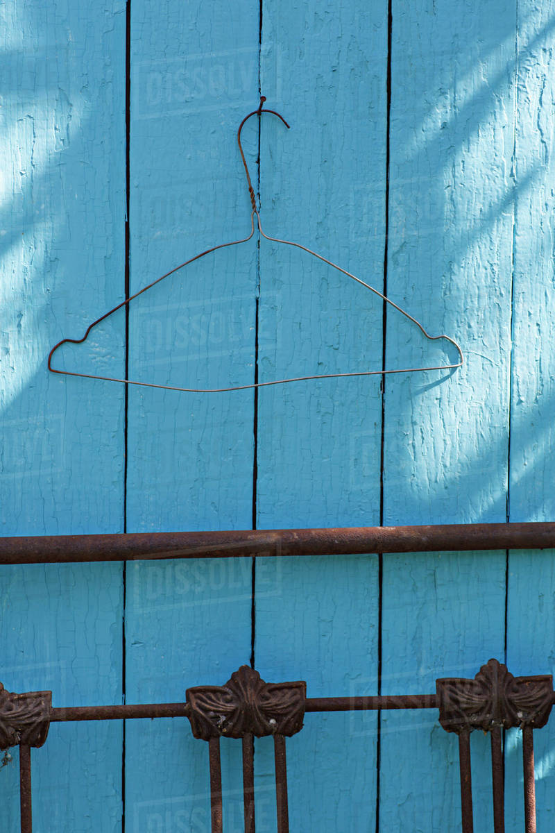 A wire coat hanger on a blue wall Stock Photo Dissolve