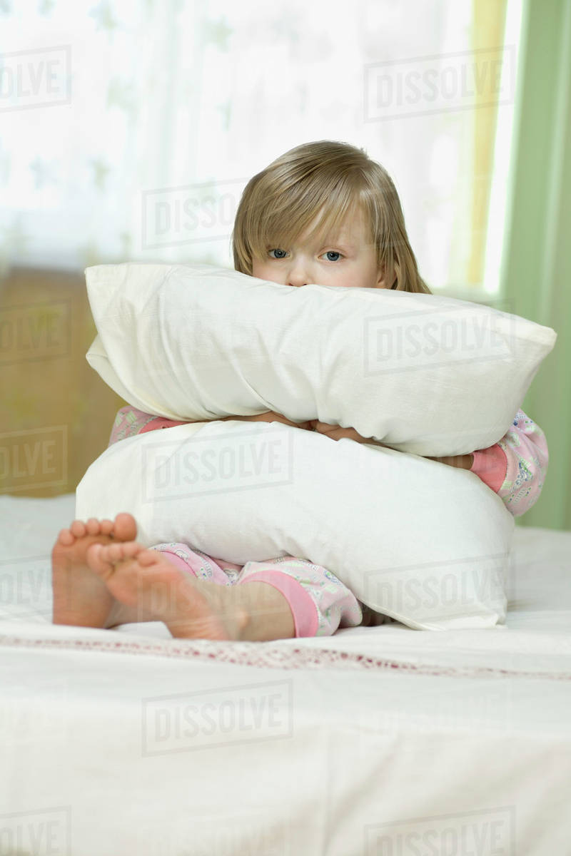 A little girl looking sad while squeezing a pillow Stock Photo Dissolve