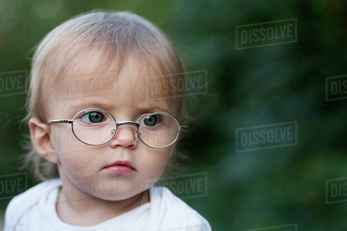 A young girl wearing glasses frowns in concentration while looking away