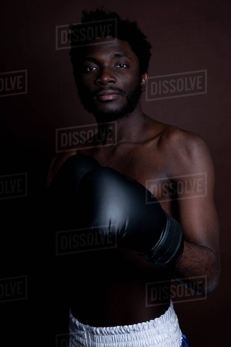 A serious young man posing in boxing shorts and boxing gloves Stock