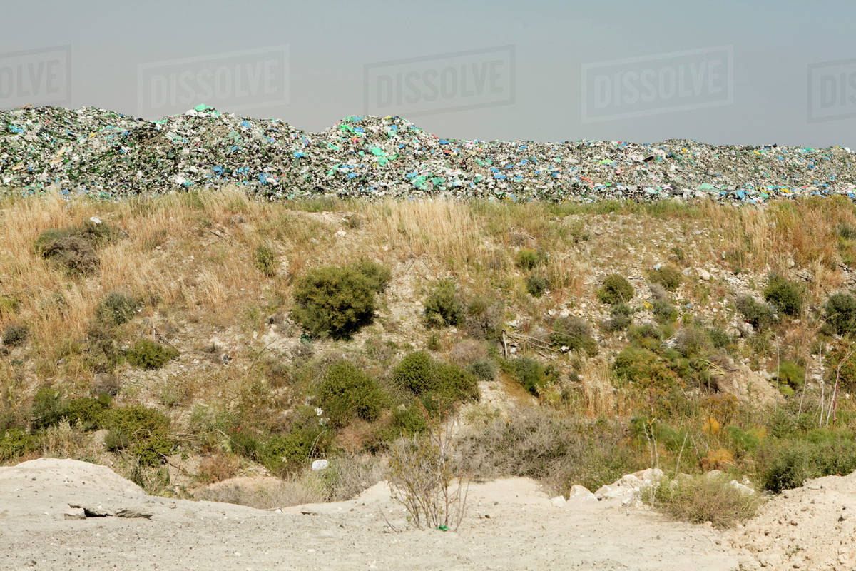 Garbage heap and field against sky Stock Photo Dissolve