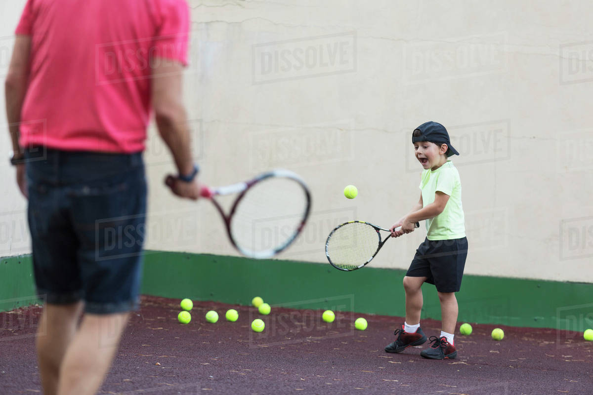 Father and son playing tennis on field Stock Photo Dissolve