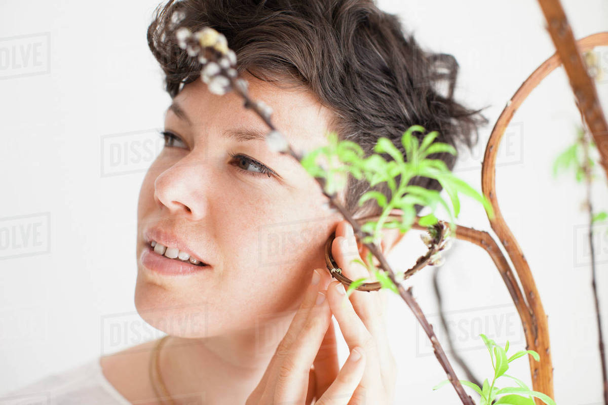 Mid adult woman feeling plant against white background Stock Photo