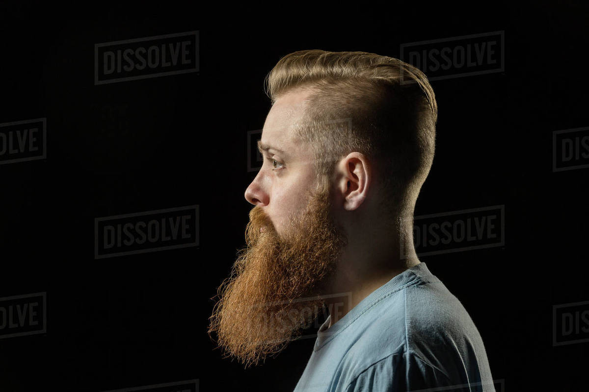 Side View Of Thoughtful Bearded Man Against Black Background