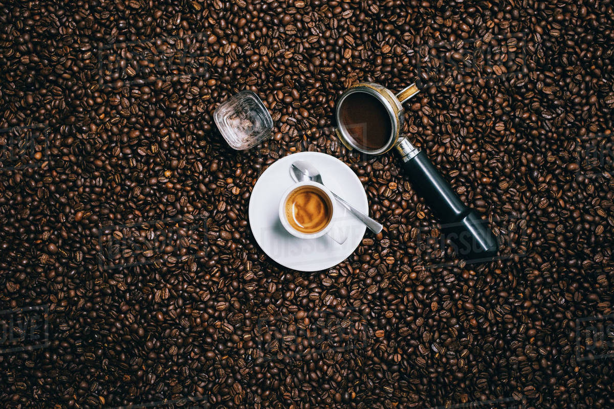 Directly above shot of espresso cup with filter on roasted coffee beans