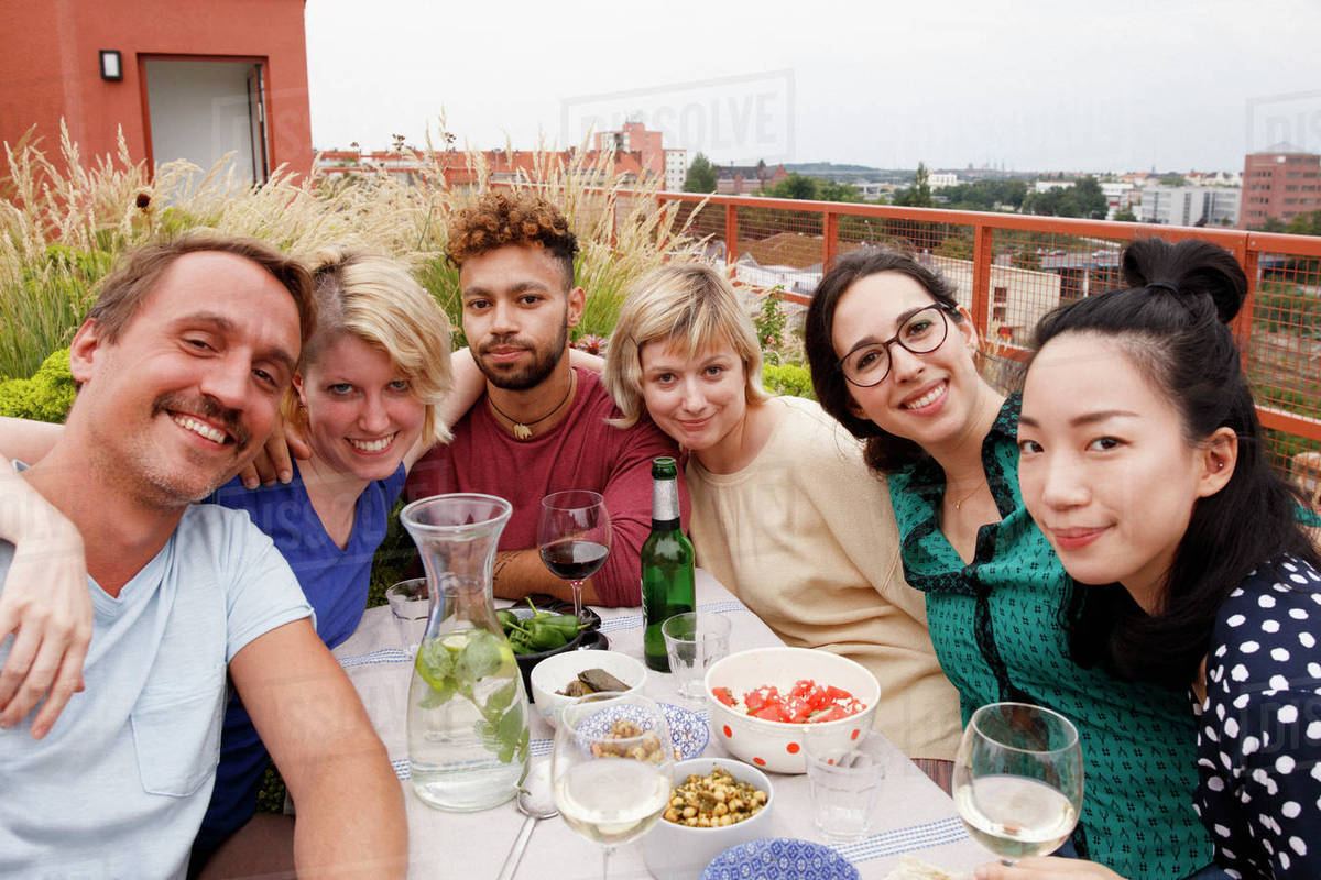 Portrait of happy friends sitting at outdoor table at patio Stock