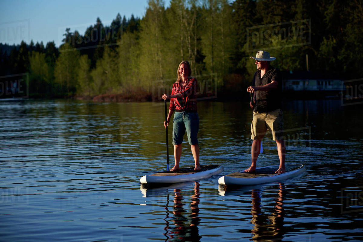 Couple standup paddleboarding on sunny lake, Shawnigan Lake, British Columbia, Canada Royalty-free stock photo