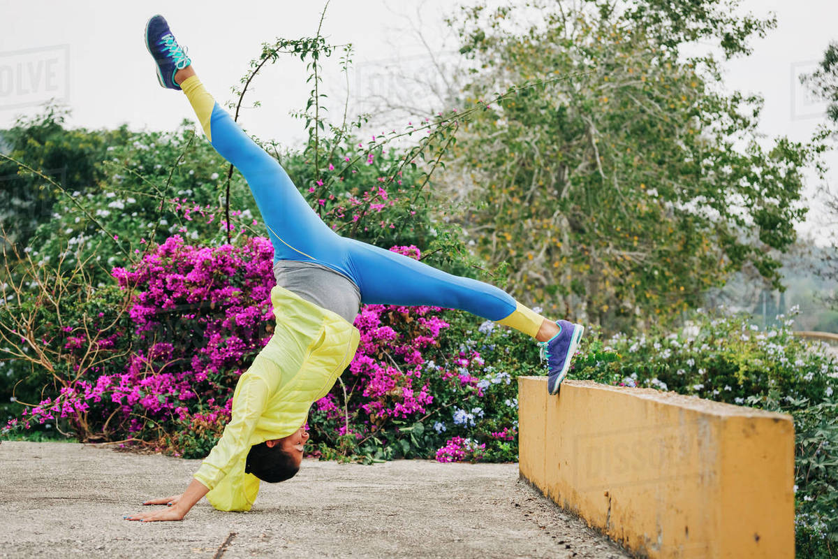 Fit female personal trainer exercising, stretching upside-down in park Royalty-free stock photo