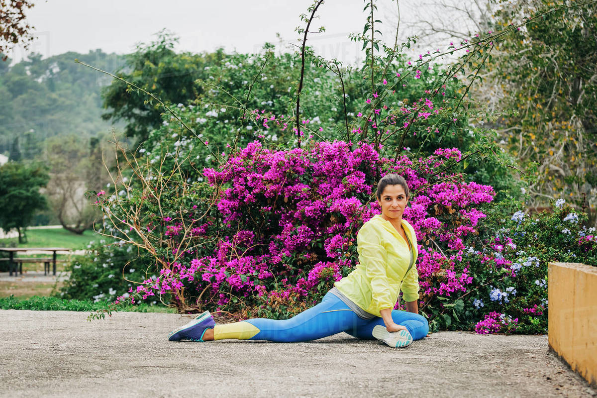 Portrait fit female personal trainer exercising, stretching in park Royalty-free stock photo