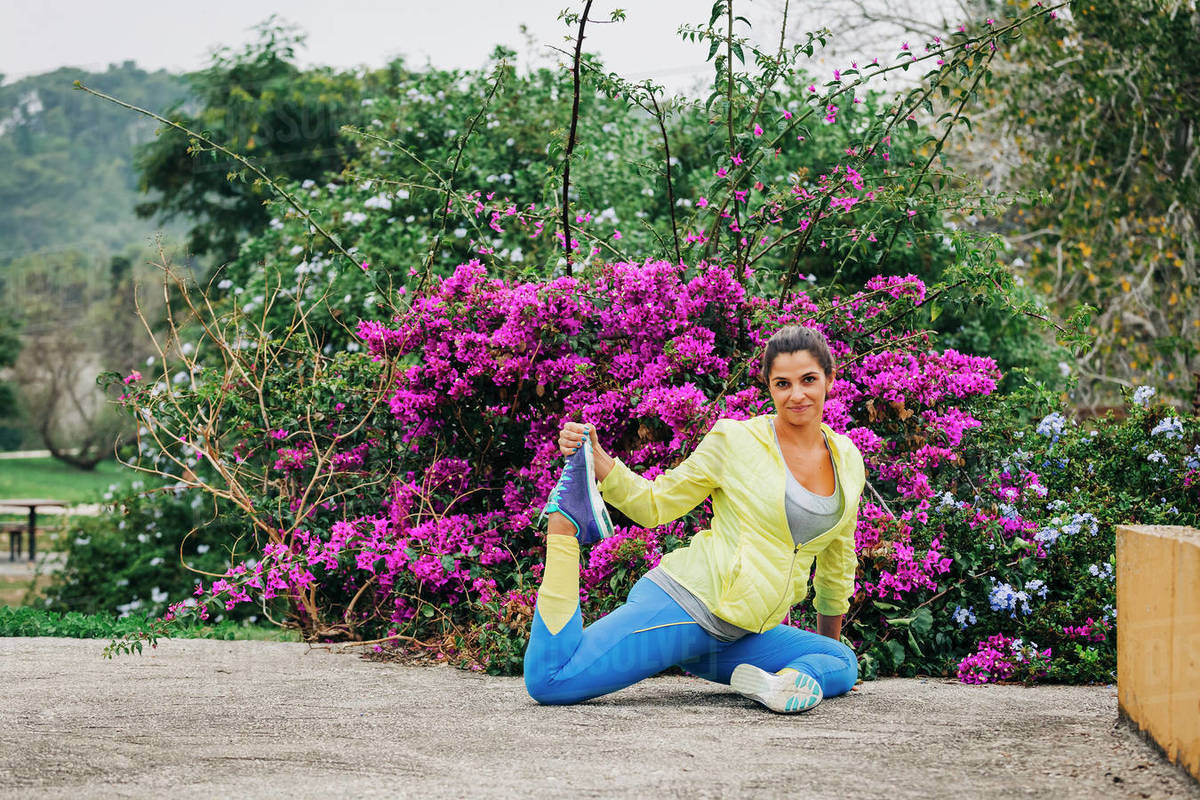 Portrait fit female personal trainer exercising, stretching in park Royalty-free stock photo