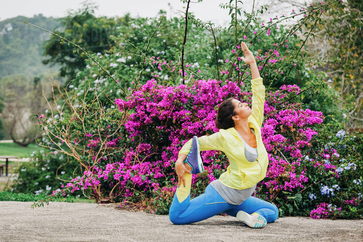 Fit female personal trainer exercising, stretching in park Royalty-free stock photo