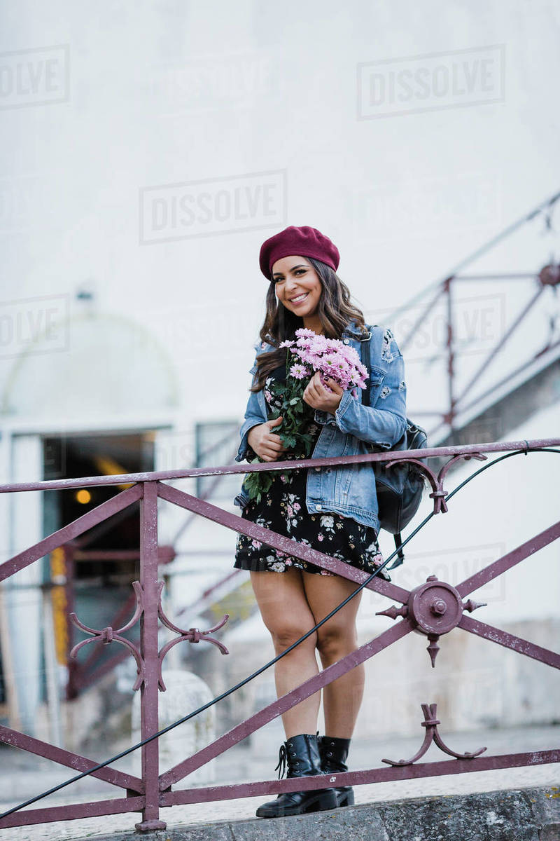 Portrait happy young woman in beret holding flower bouquet Royalty-free stock photo