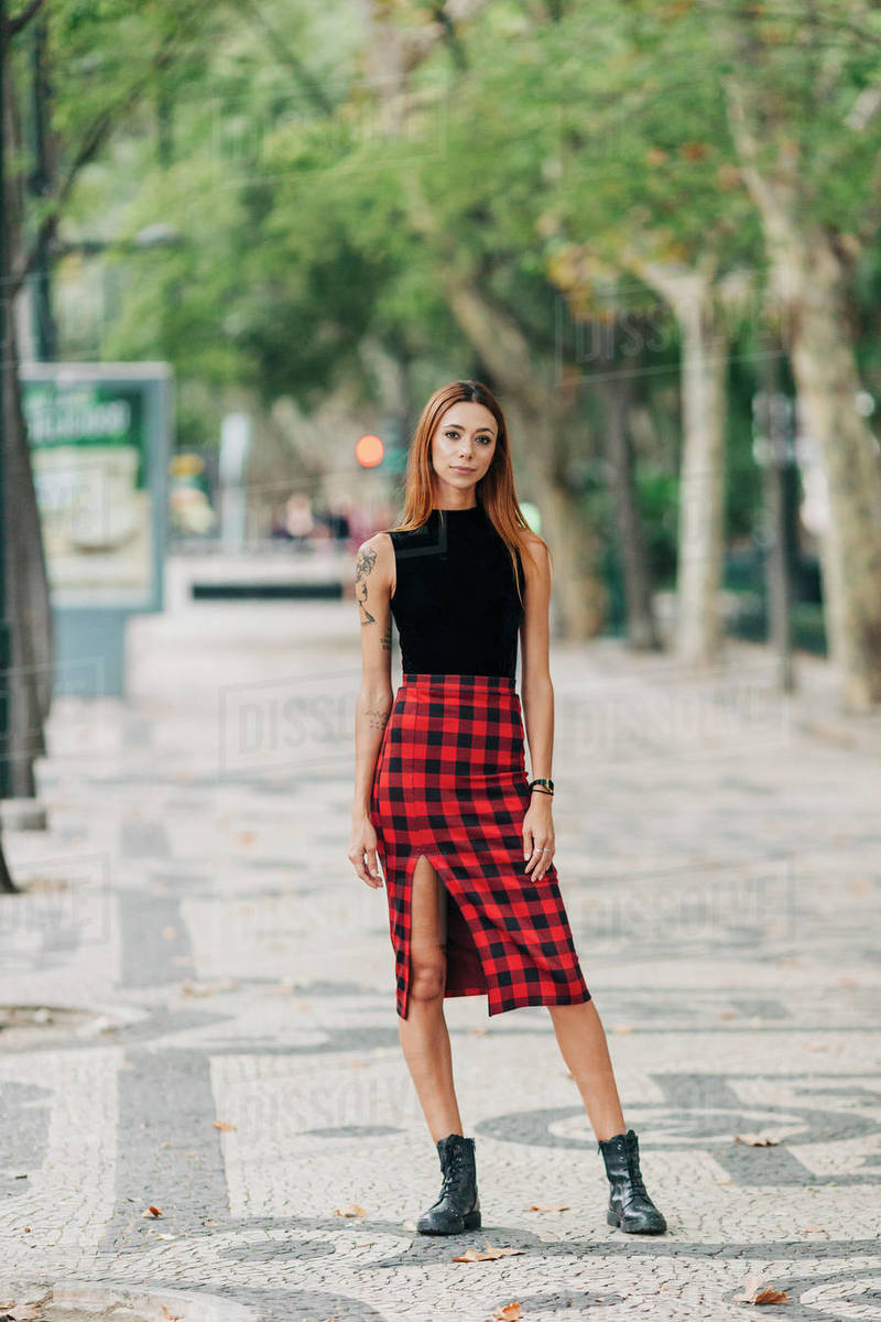 Portrait confident, stylish young woman wearing checked skirt in urban park Royalty-free stock photo