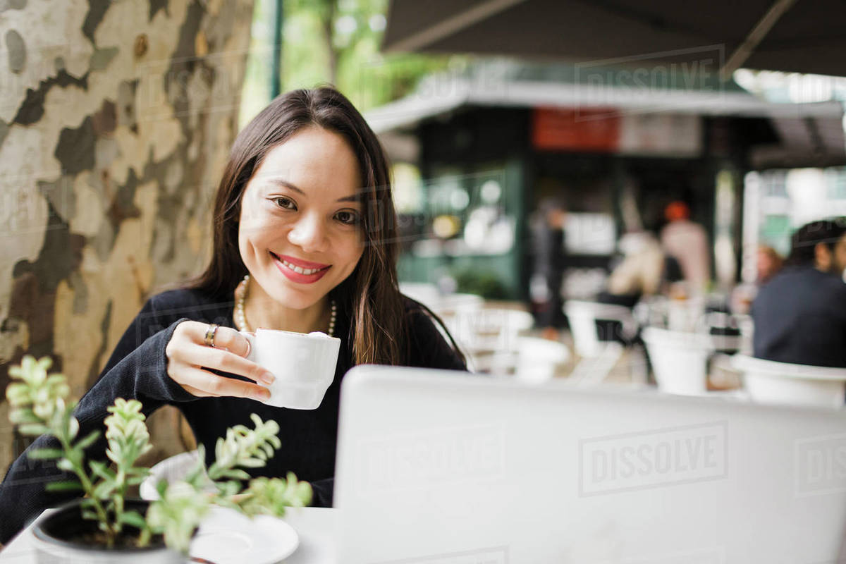 Portrait confident woman drinking coffee at laptop on sidewalk cafe Royalty-free stock photo