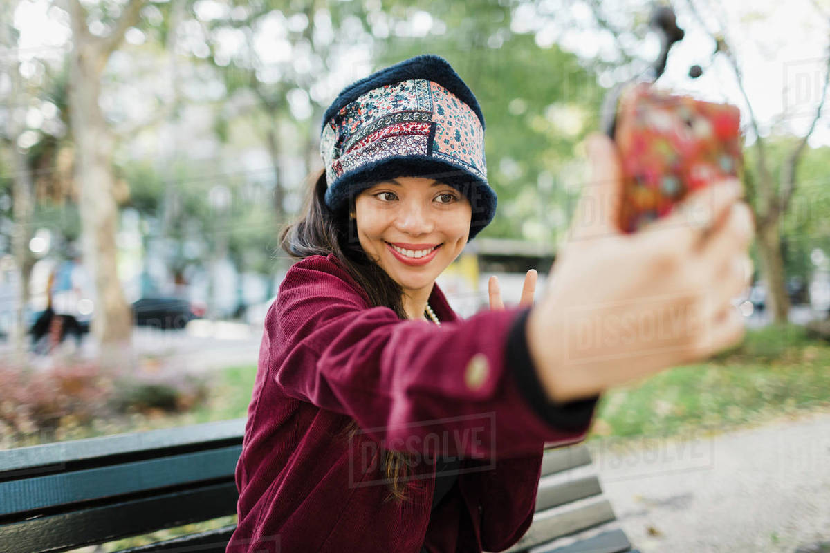 Happy woman taking selfie with camera phone on park bench Royalty-free stock photo