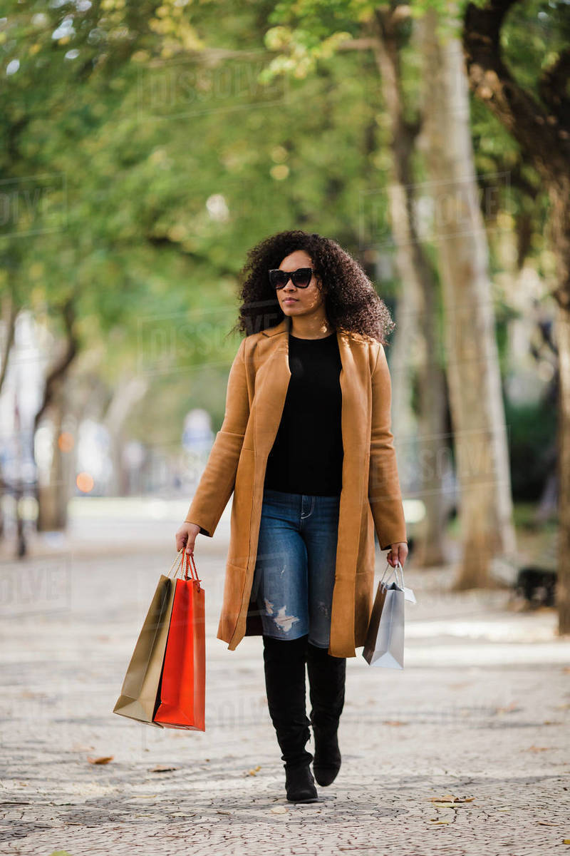 Stylish young woman walking with shopping bags on sidewalk Royalty-free stock photo