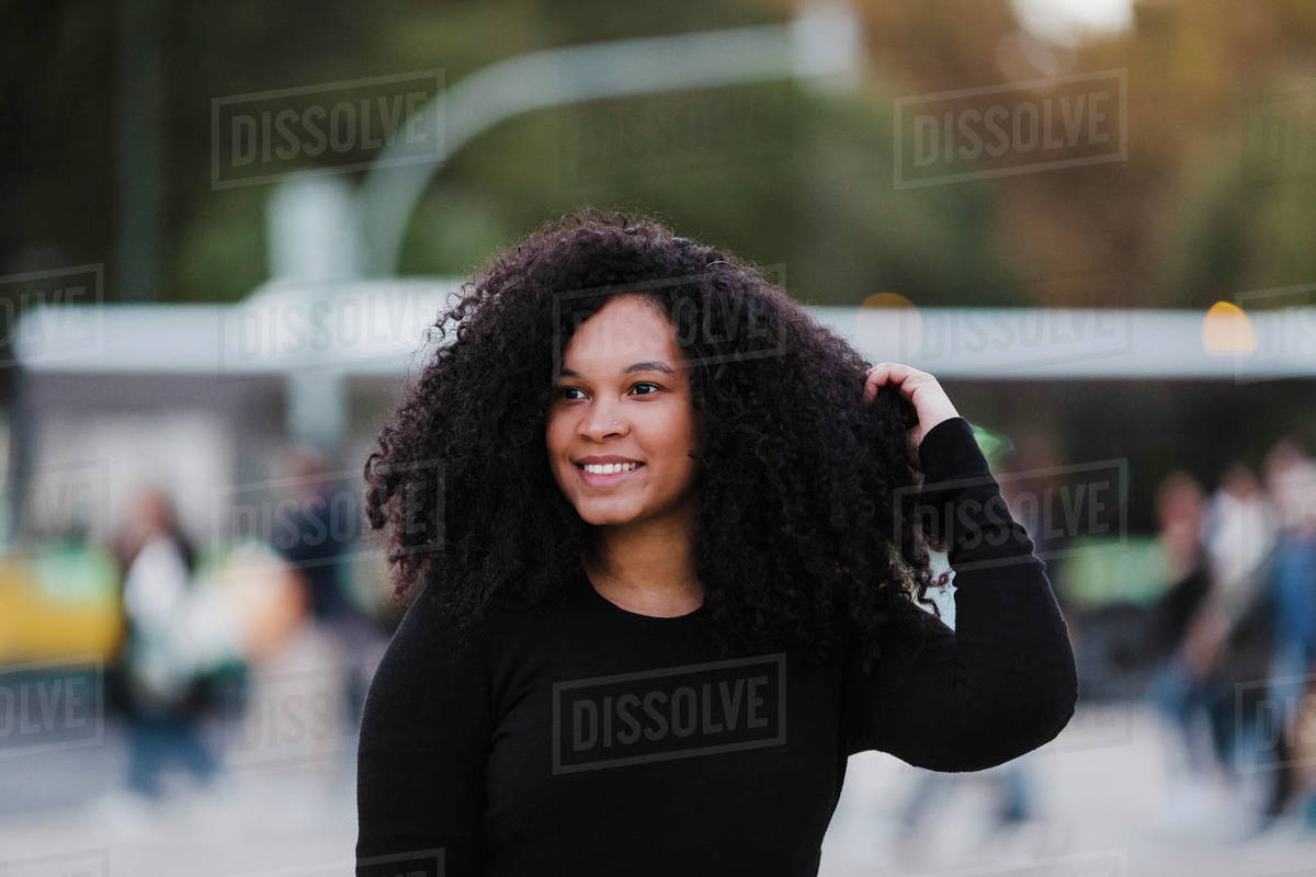 Portrait confident young woman with hand in hair on urban street Royalty-free stock photo