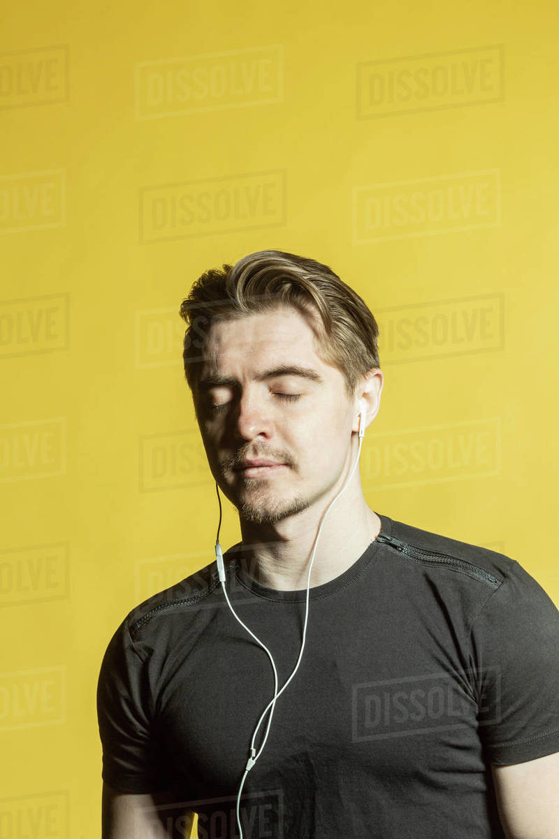 Serene man with headphones listening to music with eyes closed Stock